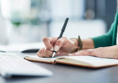 Cropped shot of a businesswoman writing in a notebook at her desk in a modern office